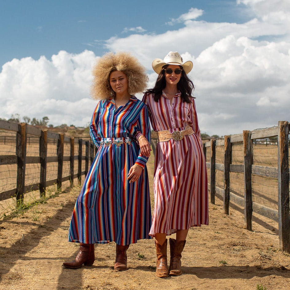 Two women in a field wearing striped outfits.