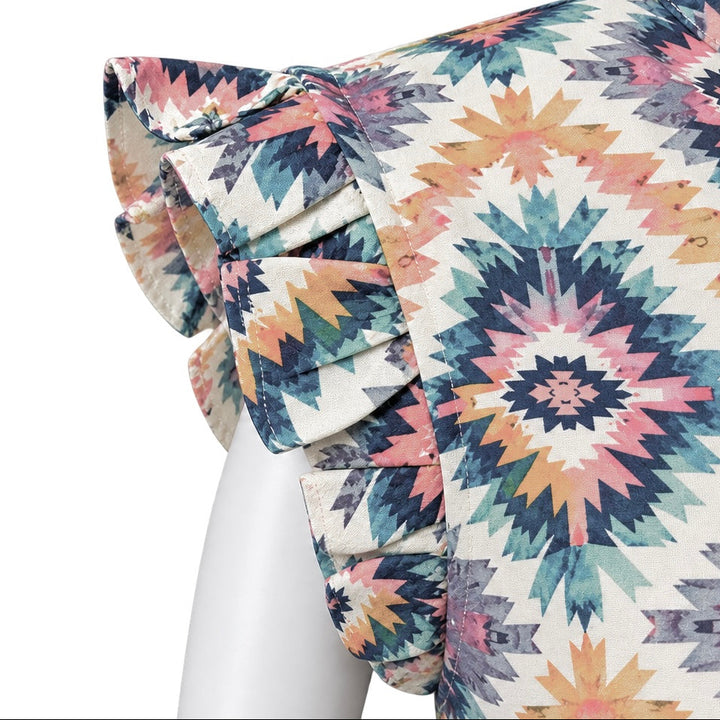 A close-up of a patterned blouse on a white mannequin, showing a ruffled sleeve with a geometric Southwestern-style print in pink, blue, orange, and gray on a cream background.