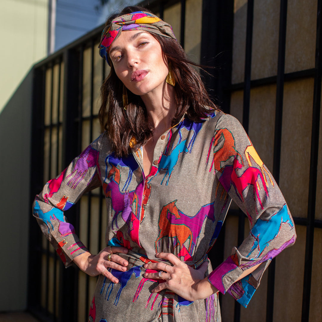 Woman wearing a colorful dress with abstract patterns standing outdoors.