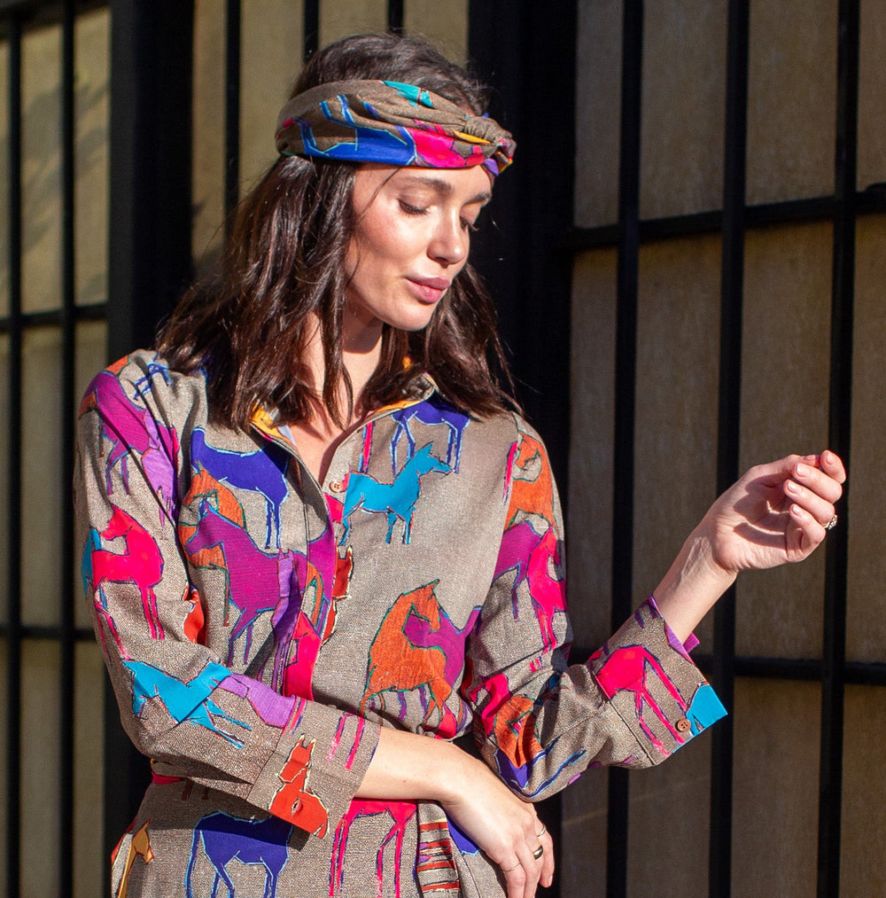 Woman wearing a colorful dress with animal prints standing on a sidewalk.