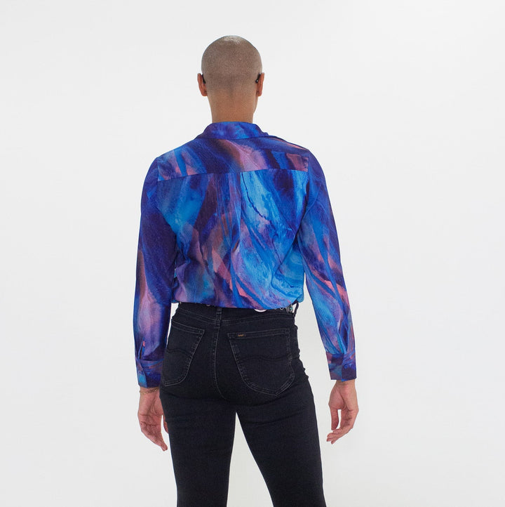 Person wearing a colorful shirt and black bell-bottom pants on a white background