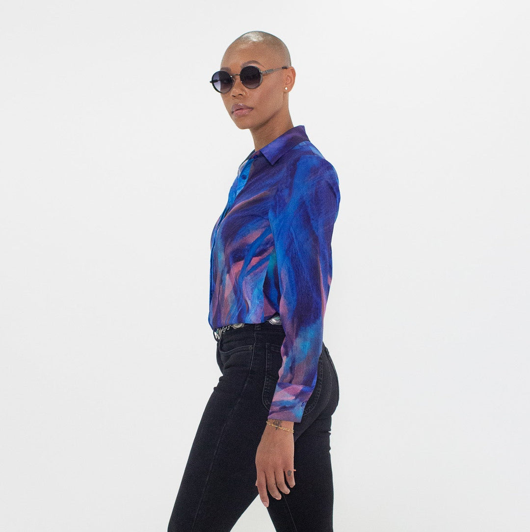 Person wearing a blue patterned shirt and black pants on a white background