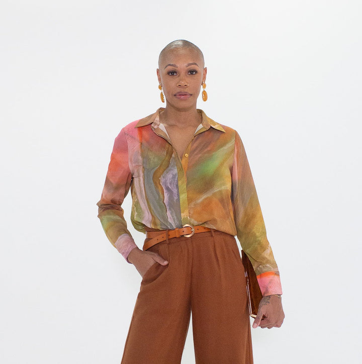 Person wearing a colorful shirt and brown wide-leg pants on a white background