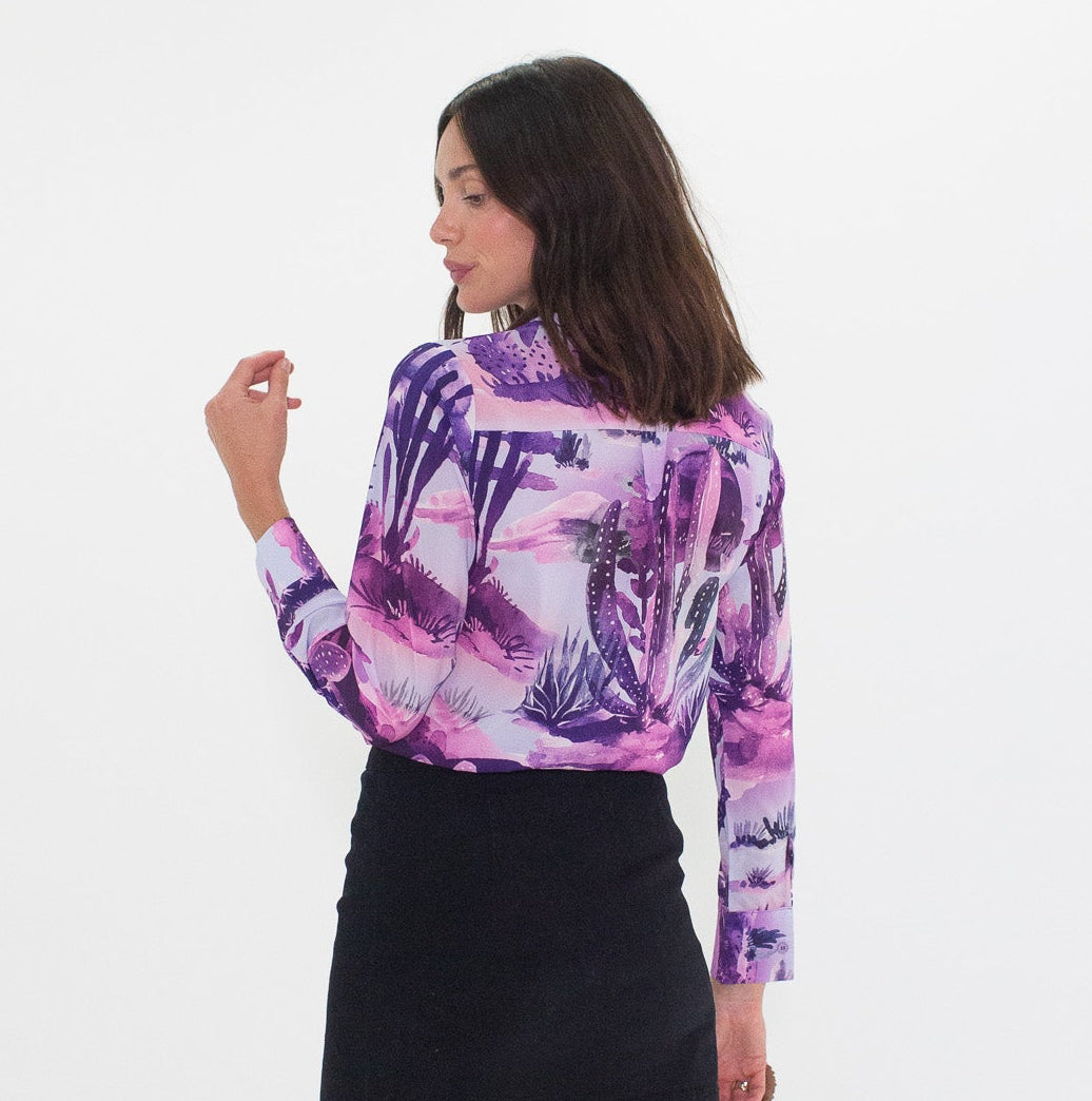 Woman wearing a purple cactus shirt, black skirt, and brown boots on a white background