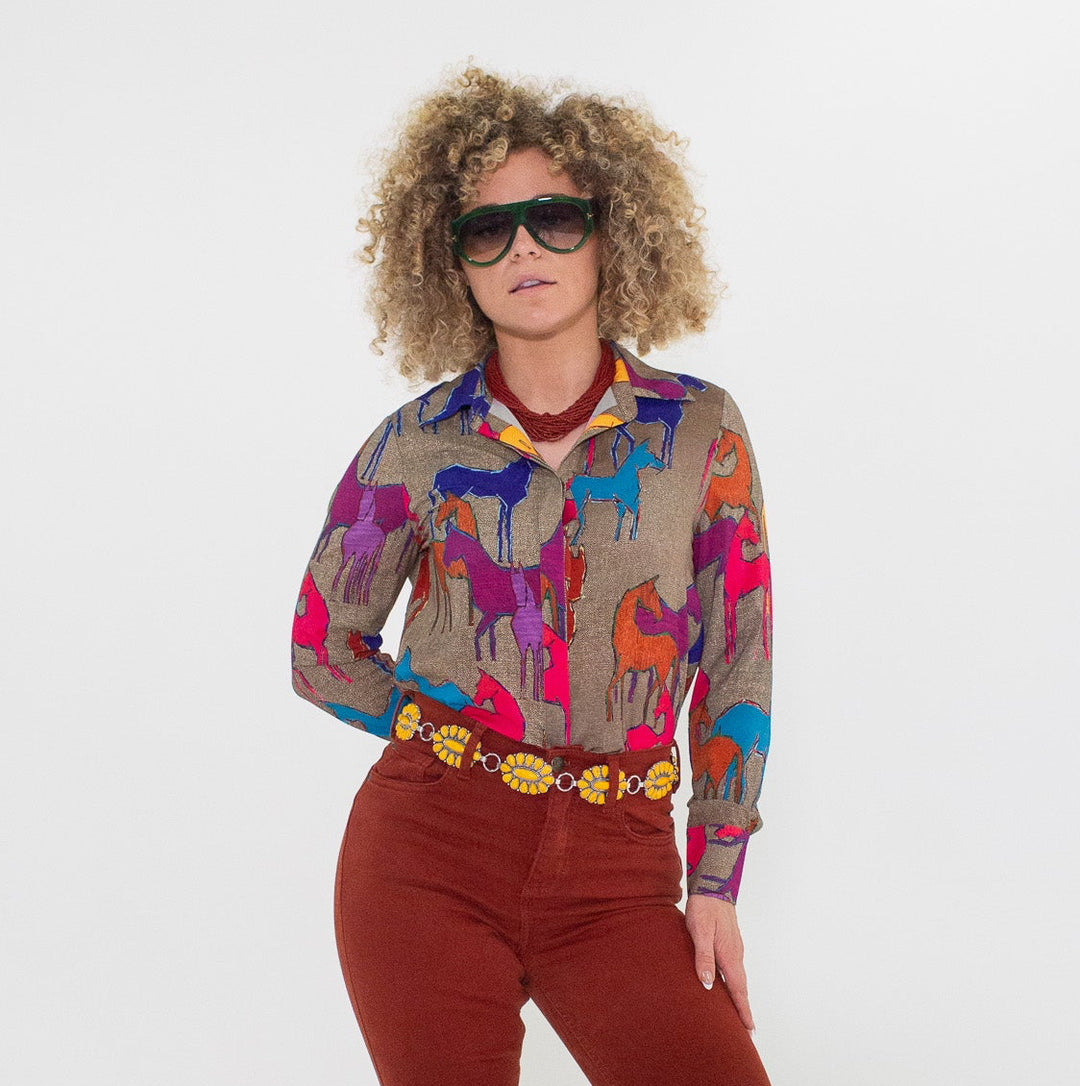 Person wearing a colorful blouse with animal patterns and red flared pants on a white background