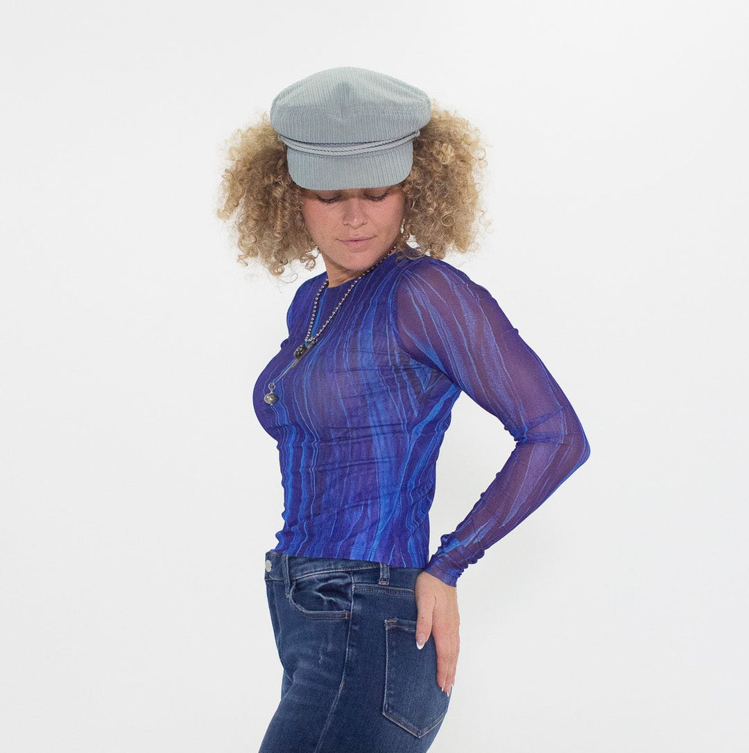 Woman wearing a blue outfit with a sheer top and flared jeans on a white background