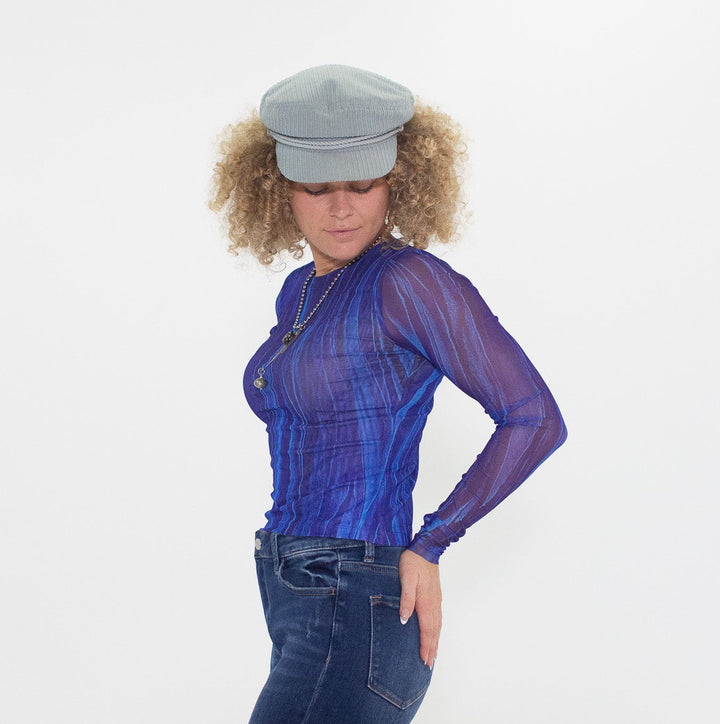 Woman wearing a blue outfit with a sheer top and flared jeans on a white background