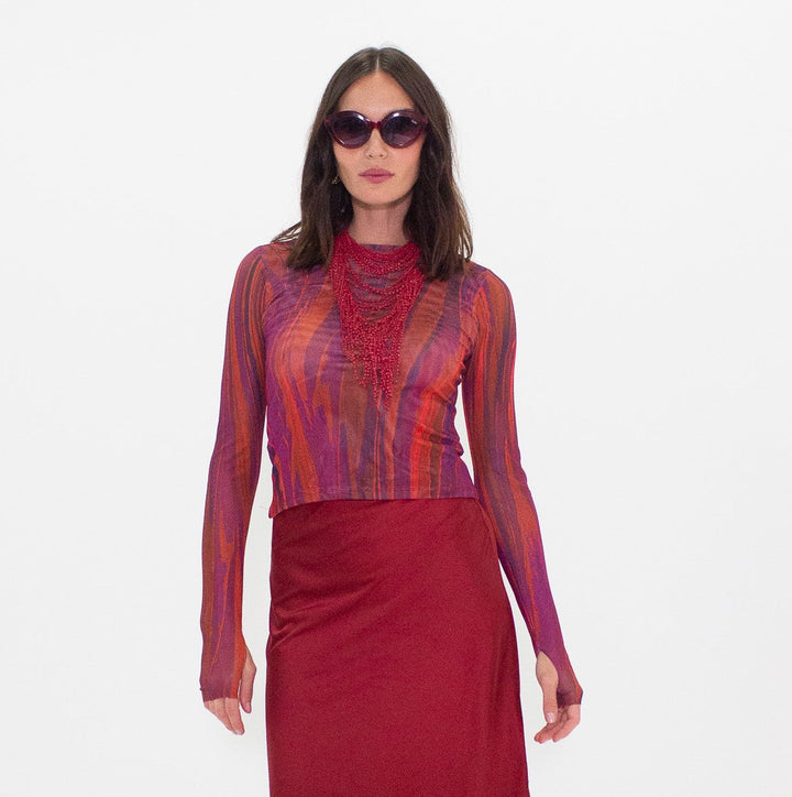 Woman wearing a colorful top and red skirt on a white background