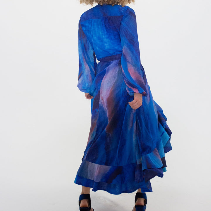 Person wearing a blue and purple dress with long sleeves on a white background