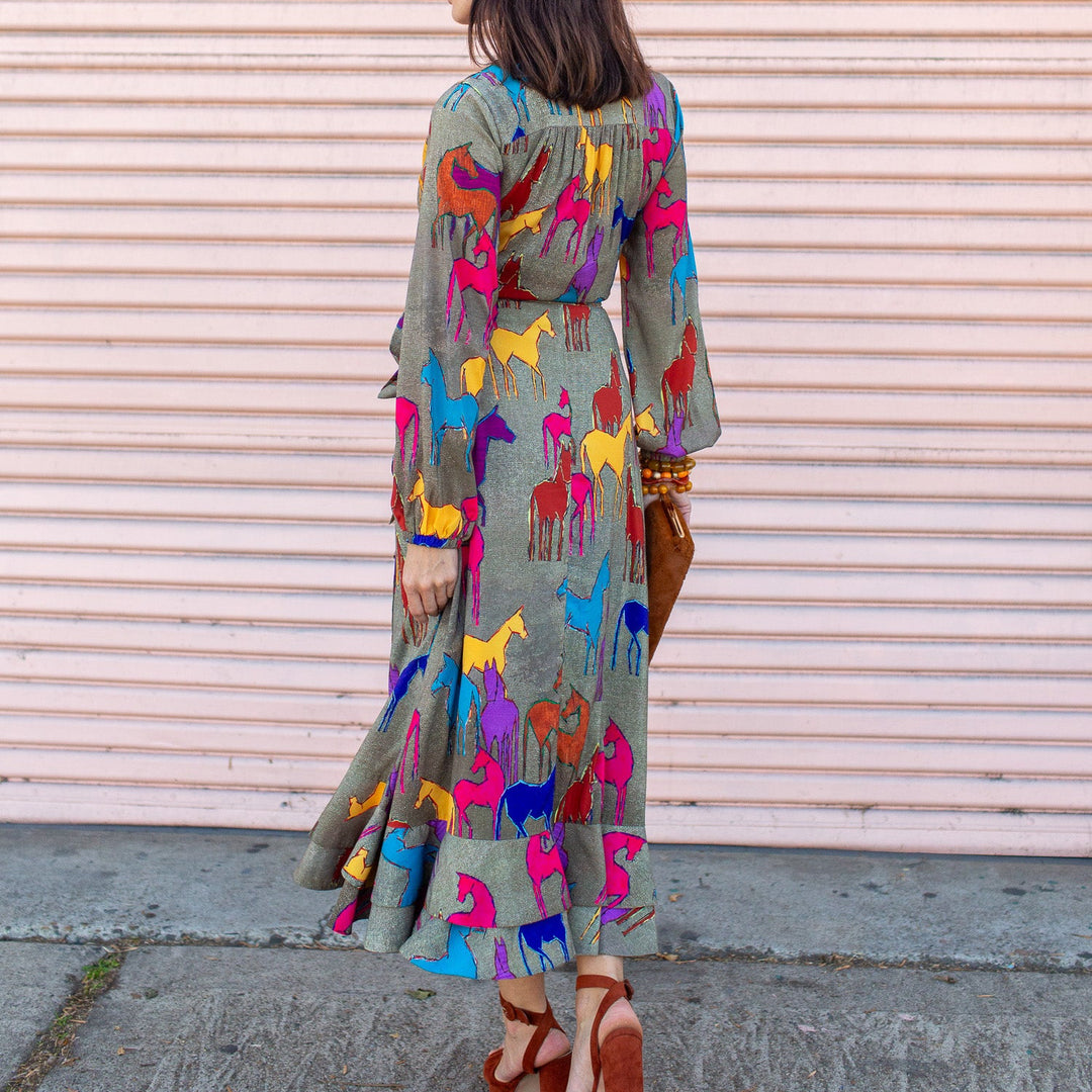 Woman wearing a colorful dress with animal patterns against a beige wall.