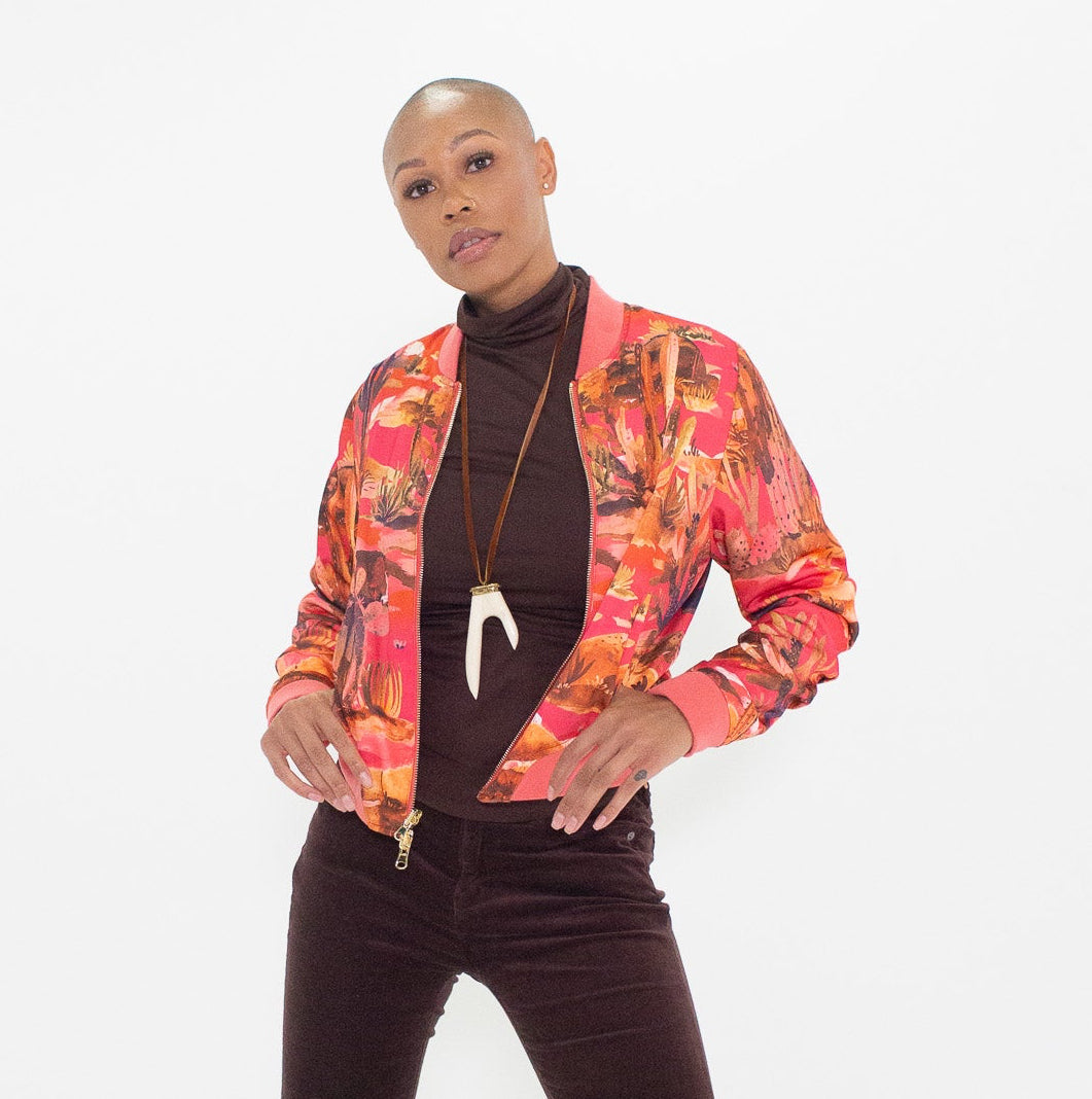 Person wearing a patterned jacket and brown bell-bottom pants on a white background