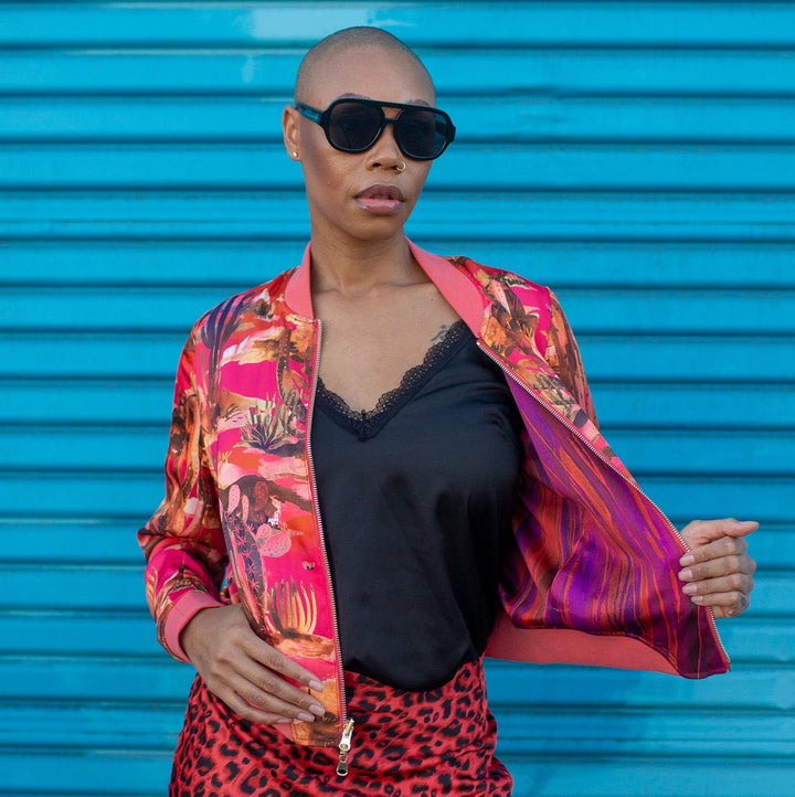 Person wearing a colorful jacket and red leopard print skirt against a blue background