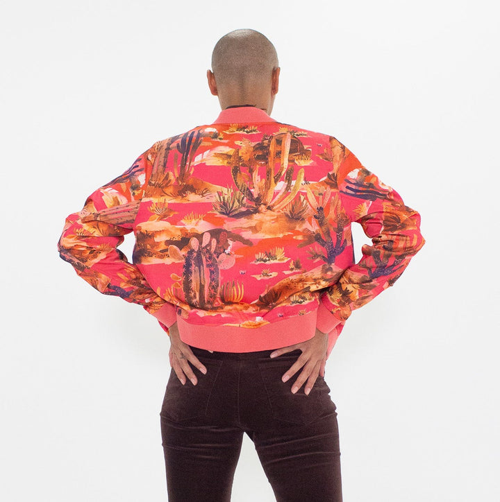 Person wearing a colorful jacket and dark flared pants on a white background
