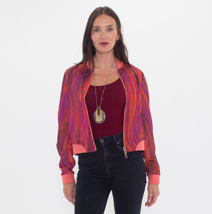 Woman wearing a colorful shirt, red top, and black flared jeans on a white background